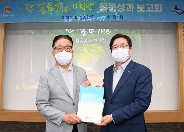 김흥식 한 걸음 더 기획단장이 염태영 시장에게 활동성과 보고서를 전달하고 있다.