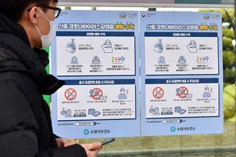영통구청 직원들이 한 버스정류소에 신종 코로나바이러스 감염증 예방수칙이 적힌 포스터를 붙이고 있다.