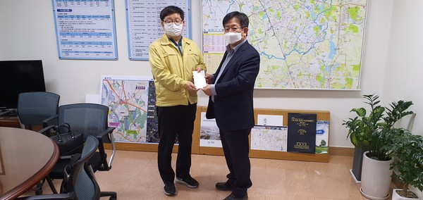 이정섭 팔달구 마을만들기협의회장(오른쪽)이 김용덕 수원시 안전교통국장에게 성금을 전달하고 있다.