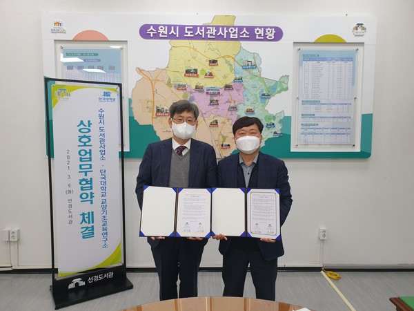 윤승준 단국대학교 교양기초교육연구소장(왼쪽)과 심언형 수원시 도서관사업소장이 업무협약서를 들어 보이고 있다.