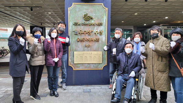 율천동 주민자치회가 지난해 제20회 전국주민자치 박람회 최우수상을 수상 기념으로 현판을 세우고 기념촬영을 하고 있다.
