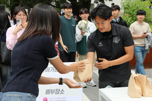 수원FC 소속 이승우 선수가 지난달 8일 기말고사 중인 아주대학교에서 열린 ‘사랑의 밥차’에서 한 여학생에게 햄버거와 음료수를 건네고 있다.